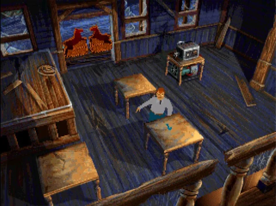 A blue-lit attic in Alone in the Dark (1992) seen from above, with the character standing between two wooden tables.