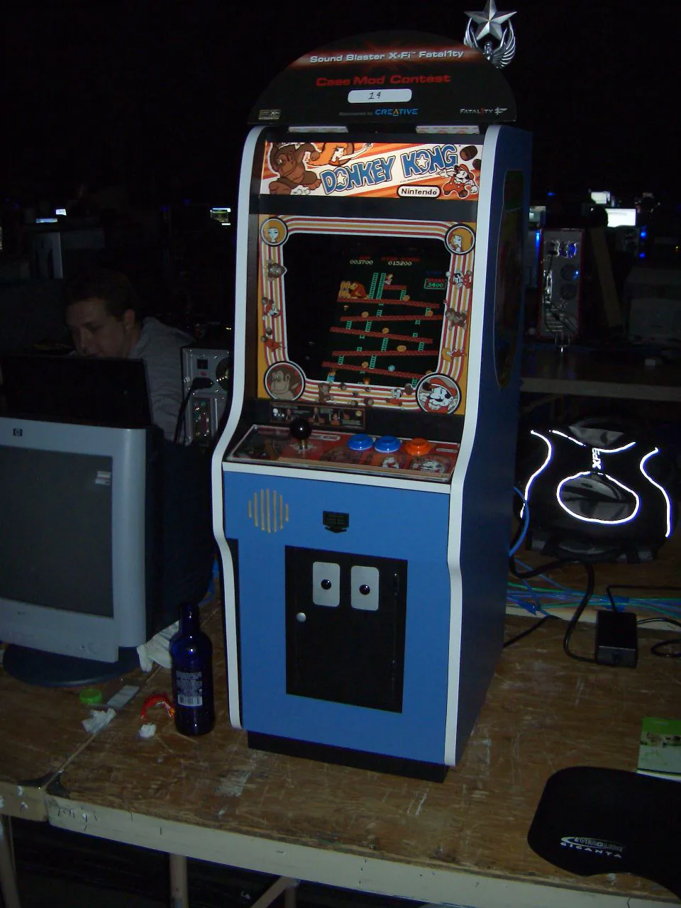 A blue Donkey Kong arcade cabinet with the game's marquee and side art, running the girder stage on a table.
