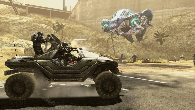 A Warthog with two armored soldiers firing at a hovering Covenant craft on a desert road