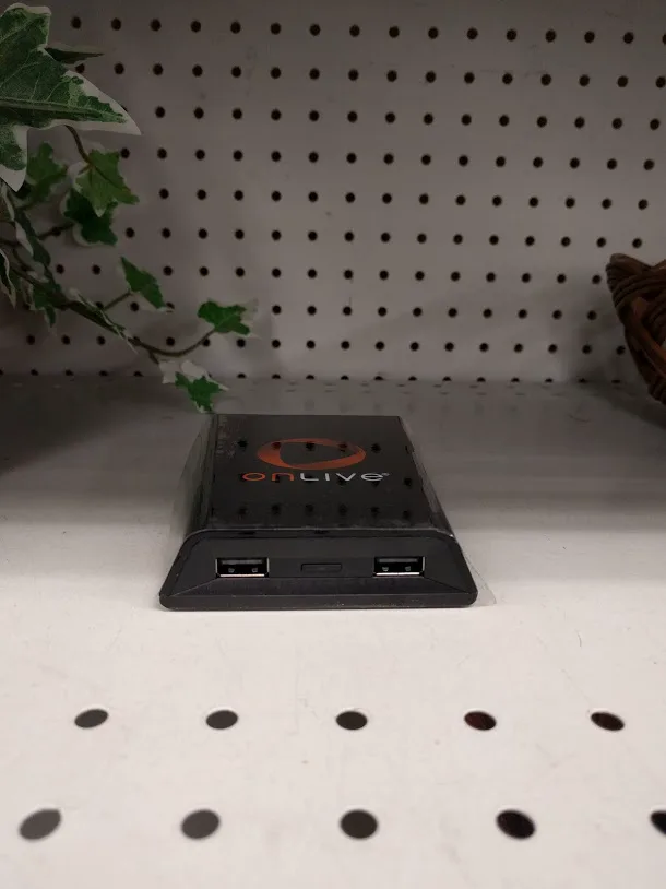 A black OnLive MicroConsole box with two USB ports on its front edge, sitting on a shelf