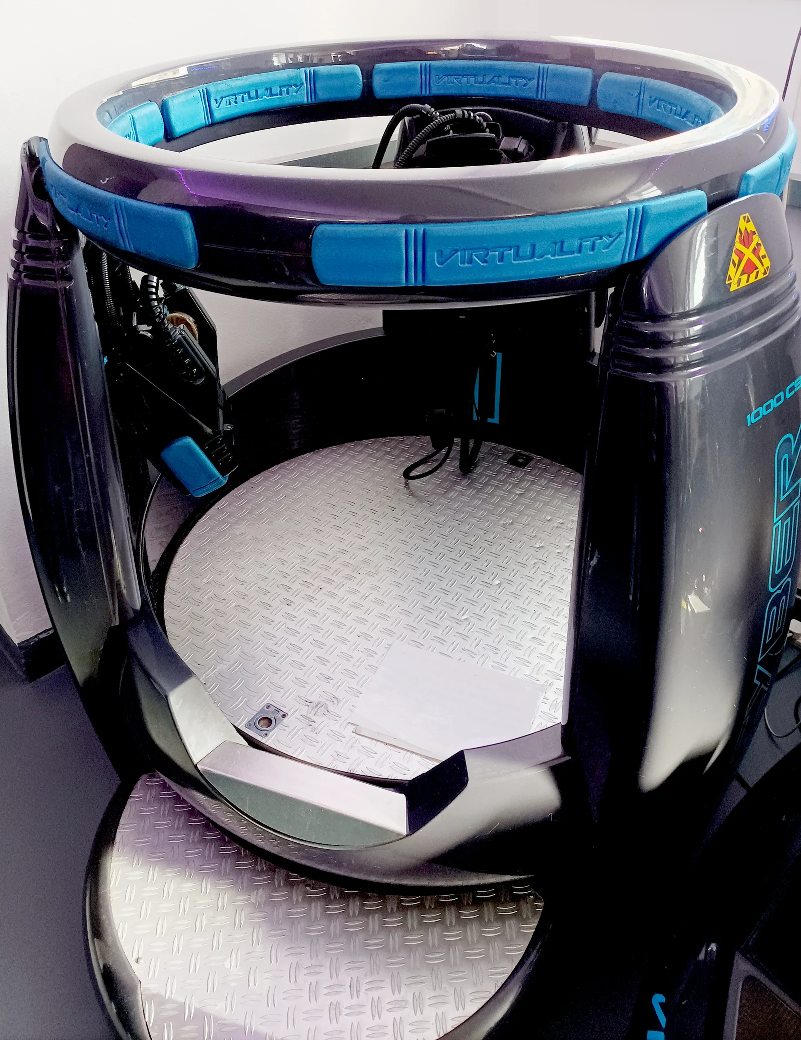 A Virtuality 1000CS arcade pod: a steel floor plate inside a raised ring padded with blue VIRTUALITY blocks.